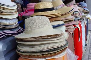 A row of summer hats arranged in different colors and styles displayed on the market stall. The hats are sorted in a way that helps customers to browse and choose the one they like. Selective focus. photo