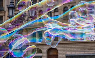 Many multicolored giant soap bubbles flying in the air on a windy day. Huge bubble are stretching on the wind into long smoothy changing form without popping. Close up. Copy space. Selective focus. photo