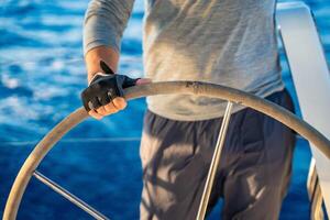 Hand of man captain stands at the helm and controls a sailboat during a journey by sea. High quality photo