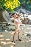 Little girl on father's hands smile and rejoice on seashore in the shade of trees and palms. Happy family concept photo