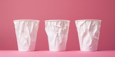 Three Crumpled White Disposable Cups On Pink Background. Collection of Crushed Paper Coffee Cups. photo