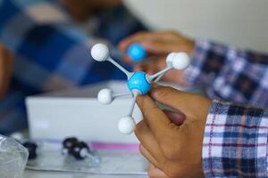 Hand holding a Simulate Shape of covalent molecules on a gray and white background. photo