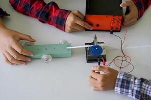 Science classroom, students are conducting a physics experiment on the speed of objects using a ticker timer device. Concept of science classroom, science skills, learning, science experiment. photo