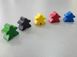 A row of colorful wooden men on a gray background. Small figures of toy wooden colorful men photo
