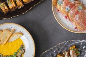 Different dishes in plates on dark background with copy space top view. Autumn menu concept photo