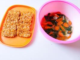 Fried tempeh and a bowl of spinach and carrots are ready to eat photo