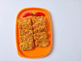 Fried tempeh is neatly lined up on a plate isolated on white photo