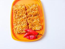Fried tempeh is neatly lined up on a plate isolated on white photo