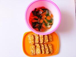 Fried tempeh and a bowl of spinach and carrots are ready to eat photo