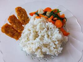 a plate of rice with tempeh and vegetables ready to eat isolate on white photo
