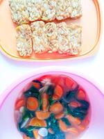 Fried tempeh and a bowl of spinach and carrots are ready to eat photo