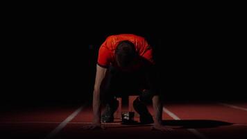 Muscular Runner Standing On Starting Blocks In Sprinter Lane, Frontal View In Dark Stadium video