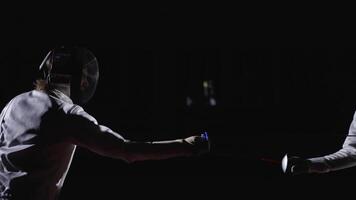 Two Fencers On Fencing Rack, Medium Side View With Two Professional Swordsmen Fighting In Darkness video