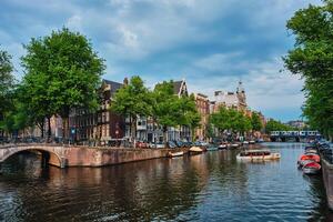Amsterdam view canal with boad, bridge and old houses photo