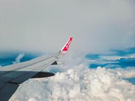 Jakarta, Indonesia, 2024 - Footage of a clear, white cloudy sky from a commercial airplane window. The view from inside the plane is a daytime sky with white clouds moving smoothly photo