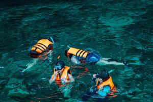 Mueang Krabi - Krabi, Thailand, 2024 - A group of tourists snorkeling around Phi-phi Island, Thailand with charming views of rocky cliffs and biota in the water photo
