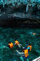 Mueang Krabi - Krabi, Thailand, 2024 - A group of tourists snorkeling around Phi-phi Island, Thailand with charming views of rocky cliffs and biota in the water photo