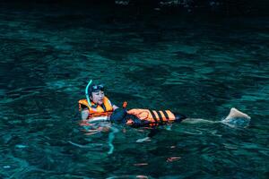 Mueang Krabi - Krabi, Thailand, 2024 - A group of tourists snorkeling around Phi-phi Island, Thailand with charming views of rocky cliffs and biota in the water photo