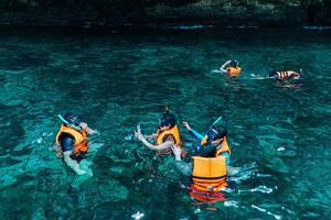 Mueang Krabi - Krabi, Thailand, 2024 - A group of tourists snorkeling around Phi-phi Island, Thailand with charming views of rocky cliffs and biota in the water photo