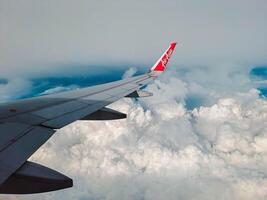 Jakarta, Indonesia, 2024 - Footage of a clear, white cloudy sky from a commercial airplane window. The view from inside the plane is a daytime sky with white clouds moving smoothly photo
