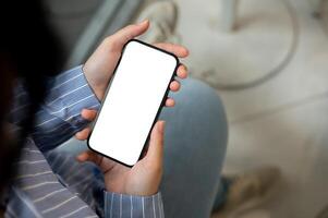A close-up image of a woman using her smartphone while sitting indoors. a smartphone mockup. photo