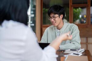 A young Asian man is having an informal meeting to discuss a project with his colleague at a cafe. photo