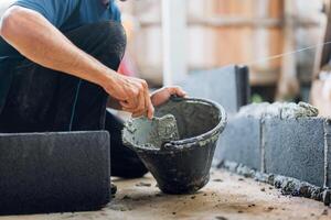 man is laying on the ground and using a trowel to spread cement photo