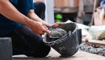 man is holding a bucket of cement and a trowel photo