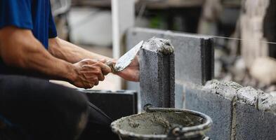 man is laying on the ground and using a trowel to spread cement photo