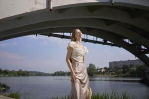 beautiful teenage girl in a silk skirt and corset in the old money style. Fashion photoshoot under the bridge. photo