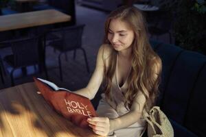 beautiful teenage girl in a peach fluffy suit with a waistcoat in the old money style reads the Holy Bible and prays photo