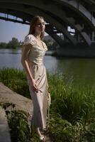 beautiful teenage girl in a silk skirt and corset in the old money style. Fashion photoshoot under the bridge. photo