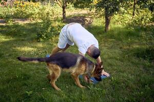 man does somatic exercises with his dog in the garden in the morning photo