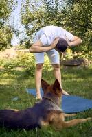 man does somatic exercises with his dog in the garden in the morning photo