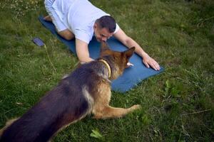 man does somatic exercises with his dog in the garden in the morning photo