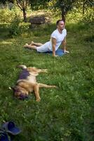man does somatic exercises with his dog in the garden in the morning photo