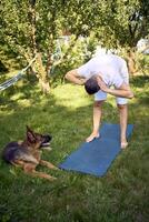 man does somatic exercises with his dog in the garden in the morning photo