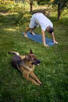 man does somatic exercises with his dog in the garden in the morning photo