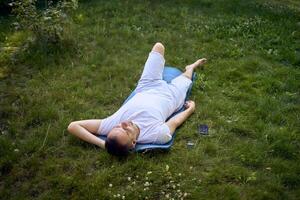 a man listens to a sound therapy playlist in headphones after somatic exercise in the morning in the garden photo
