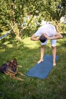 man does somatic exercises with his dog in the garden in the morning photo