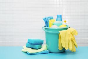Cleaners and detergents in bucket, accessories for cleaning various surfaces and rooms blue background photo