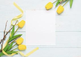 Happy Easter concept spring yellow tulips on white leaf frame pastel background. Easter background photo
