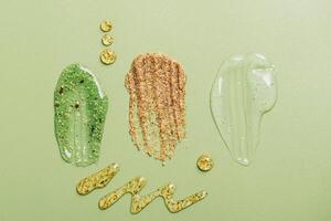 Smears samples of various cosmetics on a pastel green background, copy space. Cosmetic texture photo