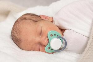 Sleeping newborn baby with pacifier white blanket, an emotional portrait of 7 days old baby photo