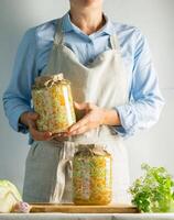 Fermentation preservation Sauerkraut in glass jars in the hands of a woman natural background. Canned food concept. photo