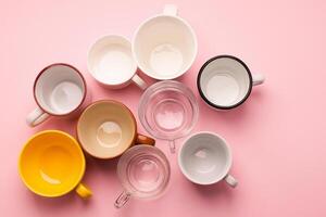 Empty cups and glasses for various drinks stand on a pink table. Flat layout top view. Drinks concept. Copy space. photo