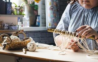 Female hands weave macrame the home workshop. Boho lifestyle. Hobby hobby concept. Selective focus horizontal frame. photo