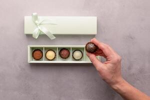 A girl holds a box of chocolates on gray background. Flat layout top view. Horizontal frame copy space photo