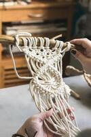 Female hands weave macrame the home workshop. Boho lifestyle. Hobby hobby concept. Selective focus photo