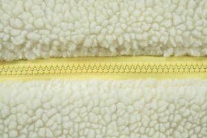 Yellow zipper on wool plush fleece fur fabric texture background photo